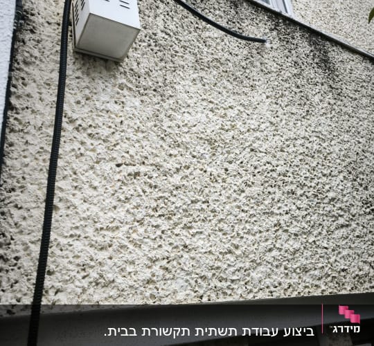 קיר חיצוני עם תיבת תקשורת וכבל מחובר
